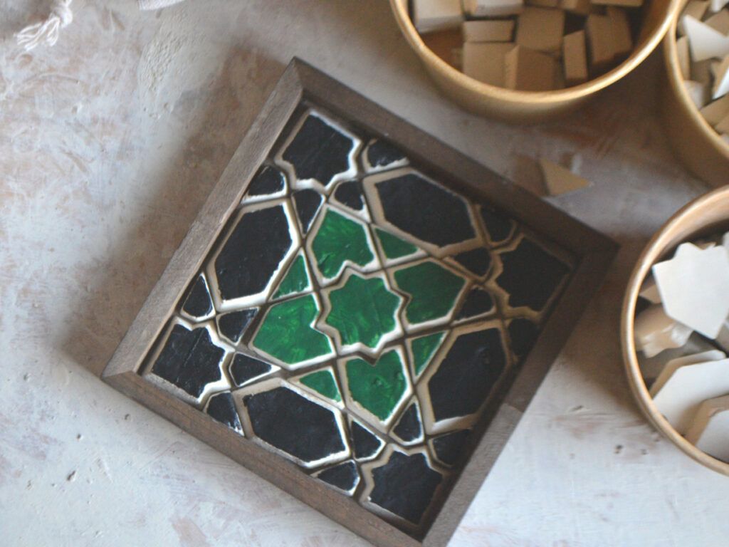 Un posavasos geométrico verde y negro en un marco de madera oscura